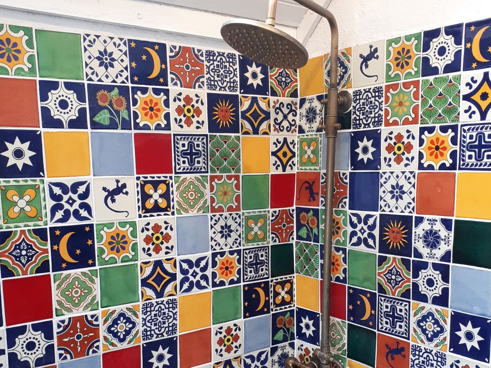 A bathroom with colorful tiles and a shower head at Taigh Phinc, Balemore near Lochmaddy, North Uist