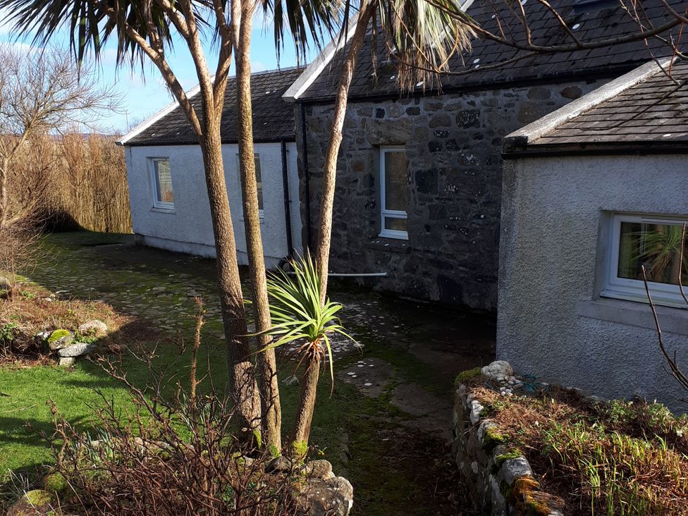 An outdoor area with trees and stone walls at Taigh Phinc in Balemore near Lochmaddy, North Uist