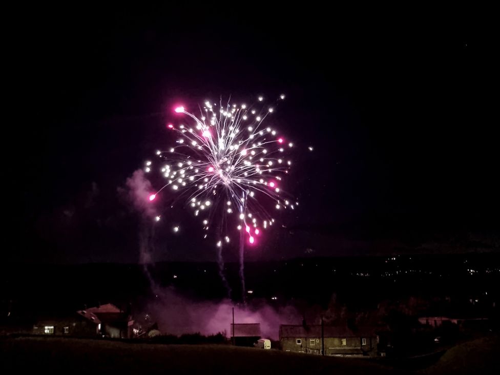 Fireworks display in the sky over houses at Popples Barn near Hebden Bridge