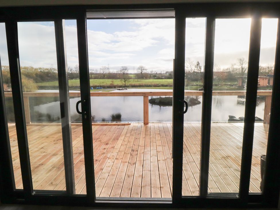 View from sliding glass doors to a deck overlooking water and trees at Lodge 6 Stockton-on-Tees