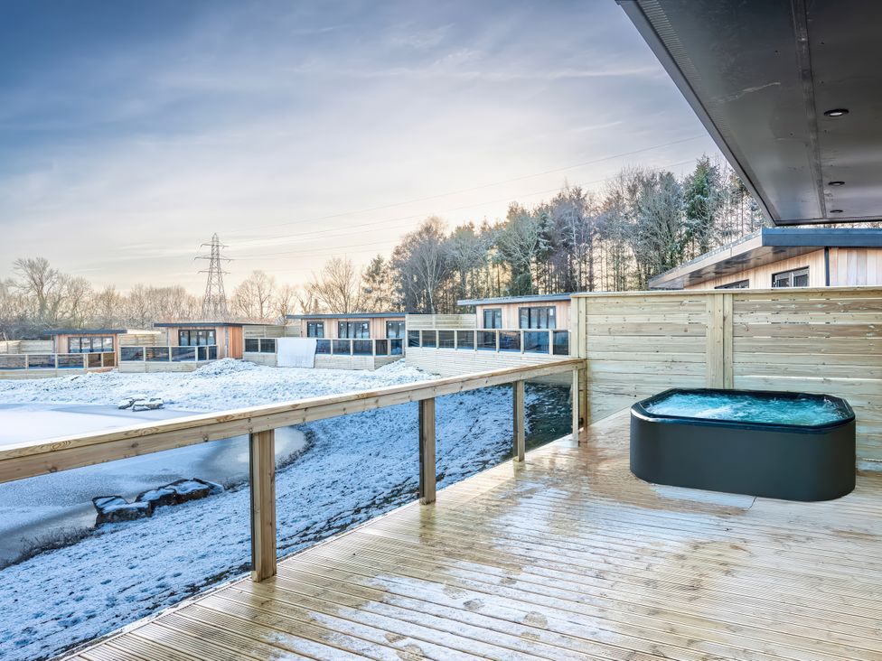 An outdoor deck with a hot tub and cabins at Lovebird Lodge in Yarm
