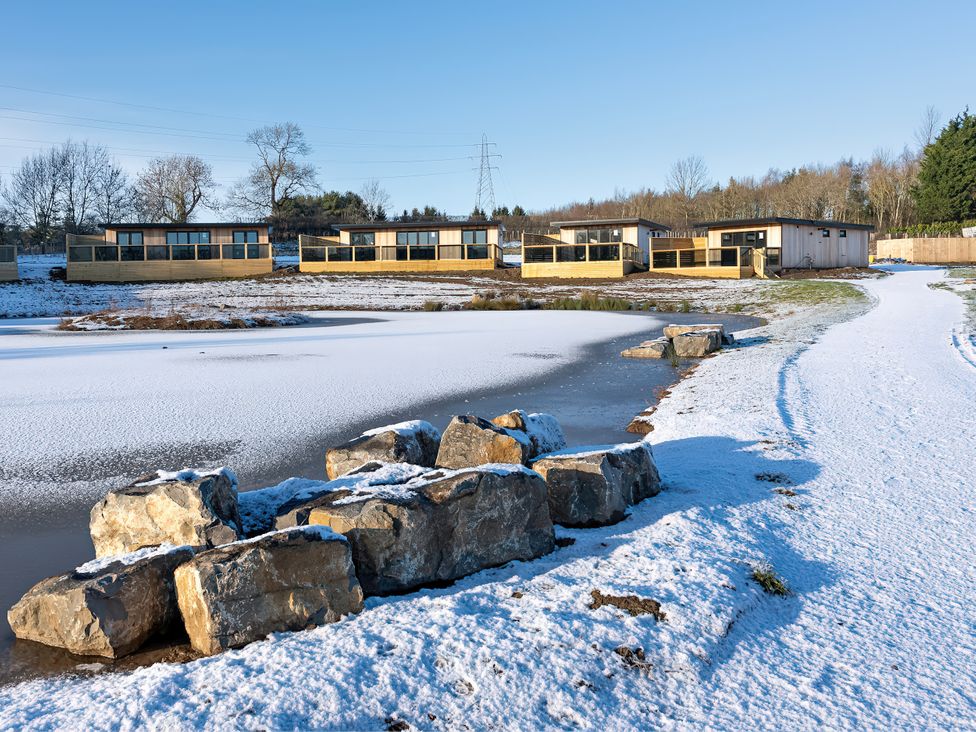 An outdoor area with cabins beside a pond at Mandarin Lodge in Yarm