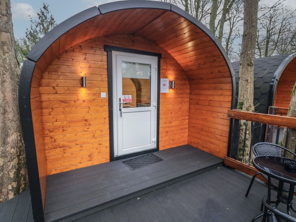 A wooden pod cabin with a white door and outdoor seating at Hawthorn in Dungiven Londonderry