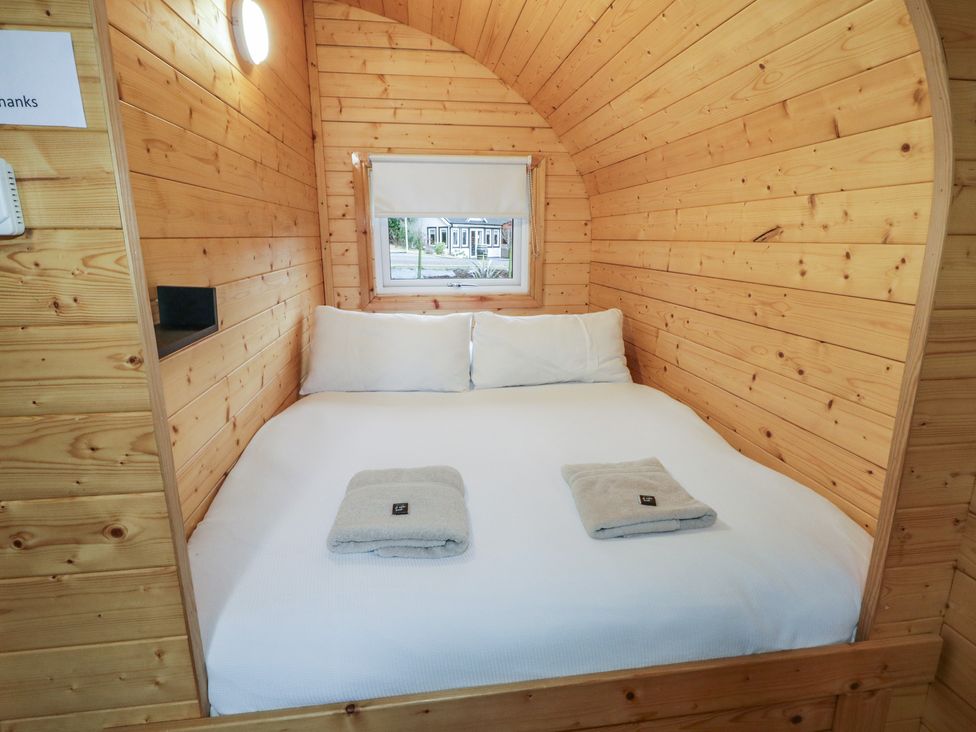 A wooden bedroom with a double bed two pillows and two folded towels on the bed at Hawthorn in Dungiven Londonderry