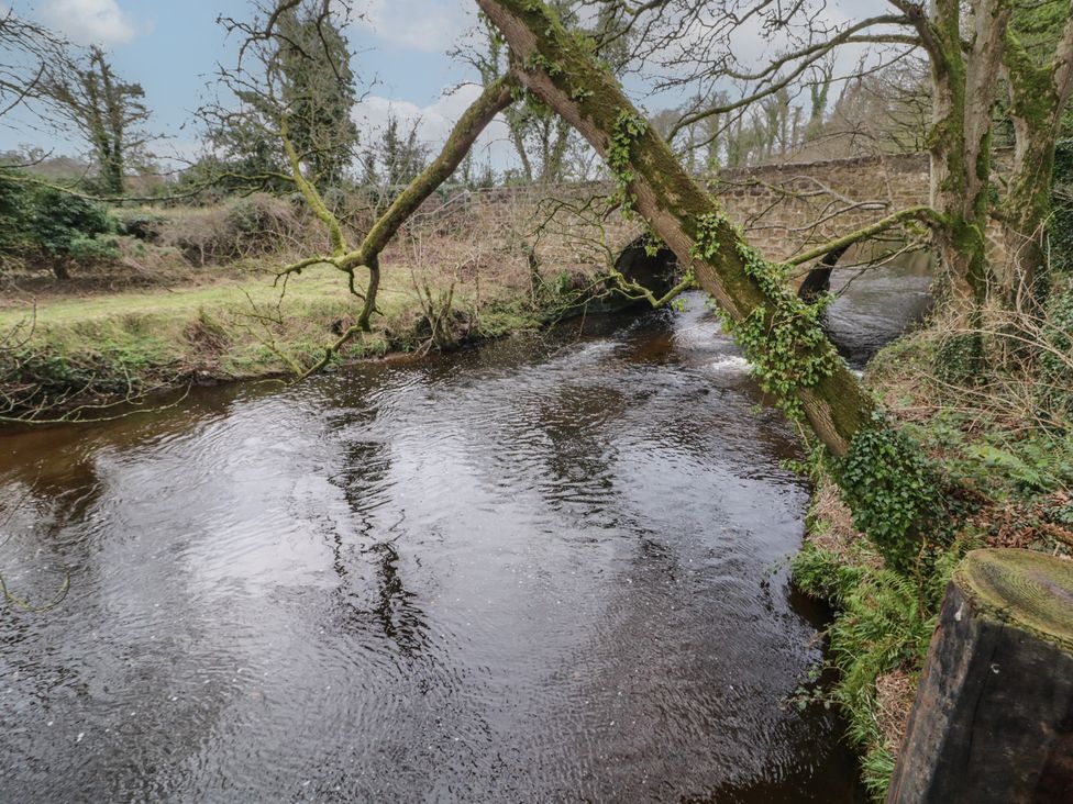 A river with trees on its banks and a stone bridge in the background at Hawthorn in Dungiven Londonderry