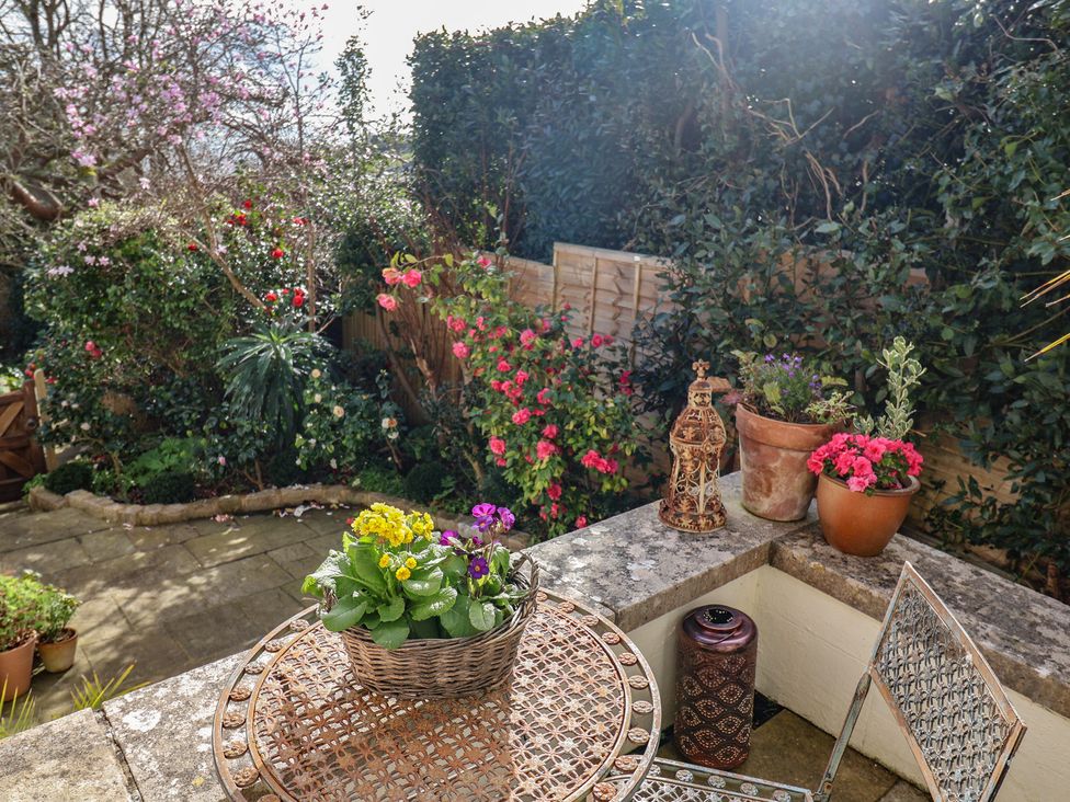 A garden with a table, chair, and flower pots at Little Sea Thrift in Lyme Regis