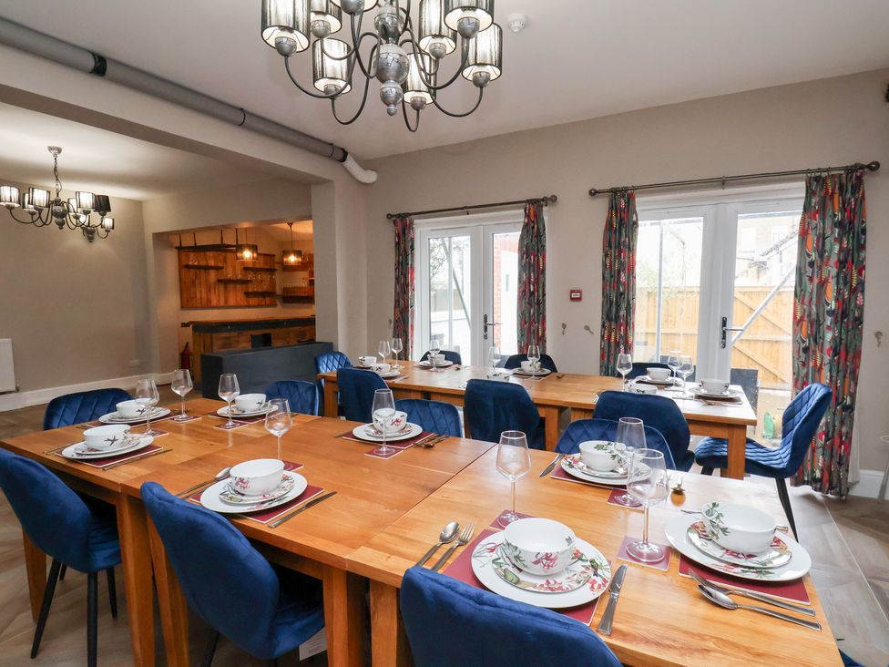 A dining room with a long table set for dinner at Rutland Grange in Filey