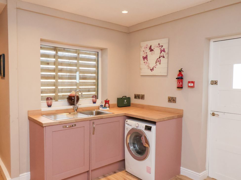 A laundry room with a sink and washing machine at Rutland Grange in Filey
