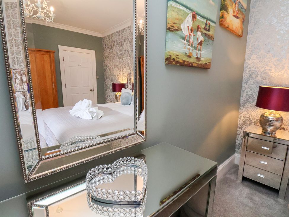 A bedroom with a mirror and bedside lamp at Rutland Grange in Filey