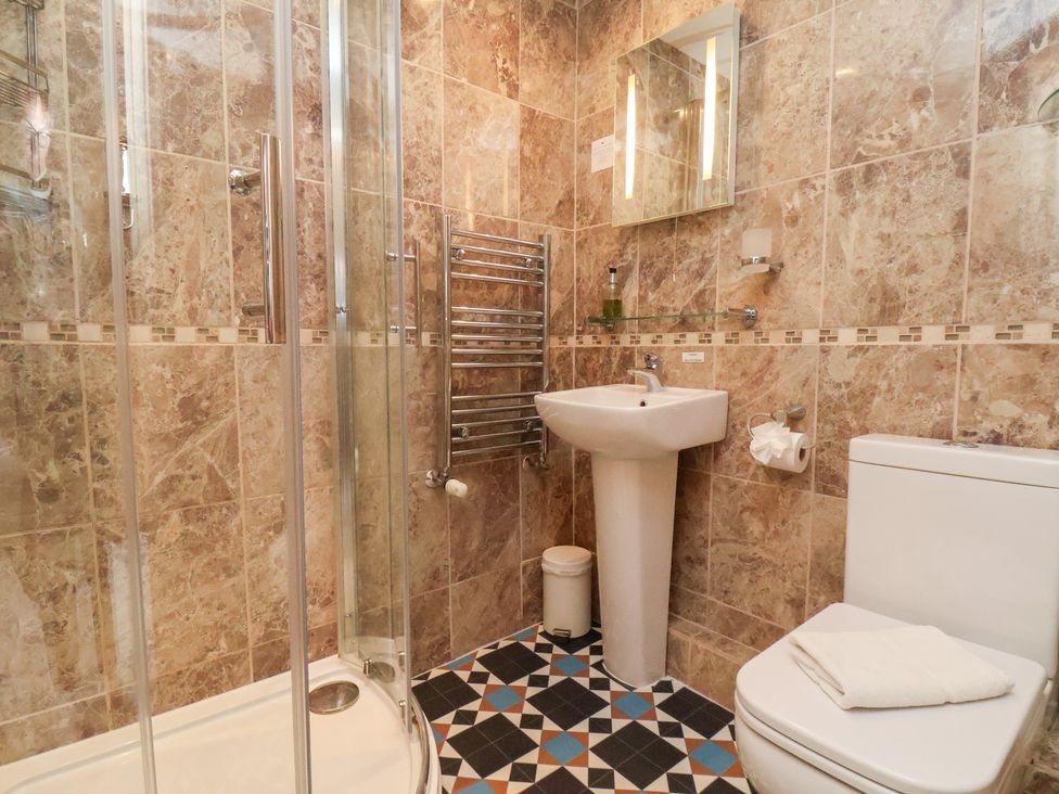 A bathroom with a shower, toilet, and sink at Rutland Grange in Filey