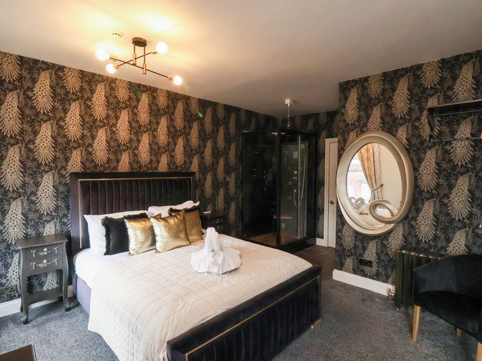 A bedroom with a bed and ensuite shower at Rutland Grange in Filey