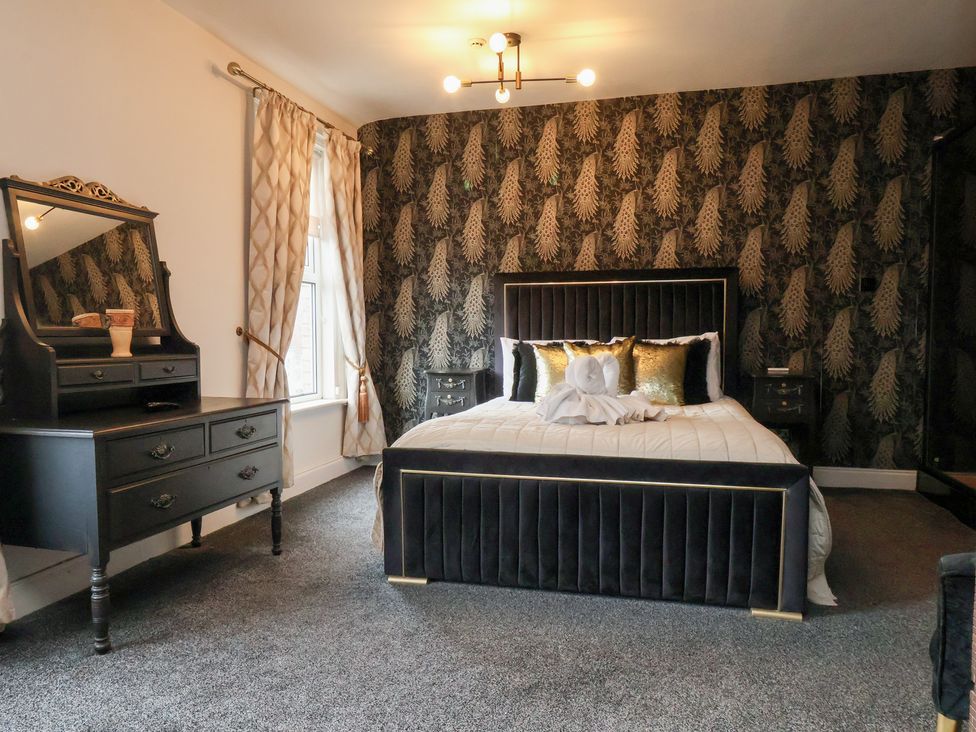 A bedroom with a bed and mirror at Rutland Grange in Filey