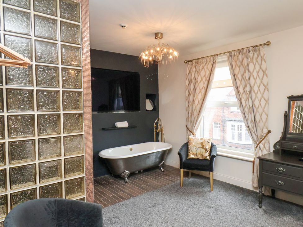 A bathroom with a bathtub and television at Rutland Grange in Filey