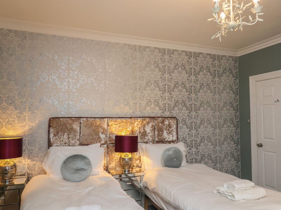 A bedroom with two beds and lamps at Rutland Grange in Filey