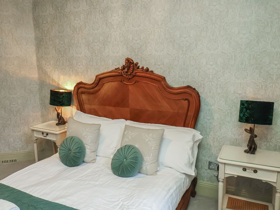 A bedroom with a wooden bed and lamps at Rutland Grange in Filey
