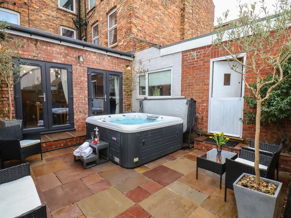 An outdoor patio with a hot tub and seating at Rutland Grange in Filey