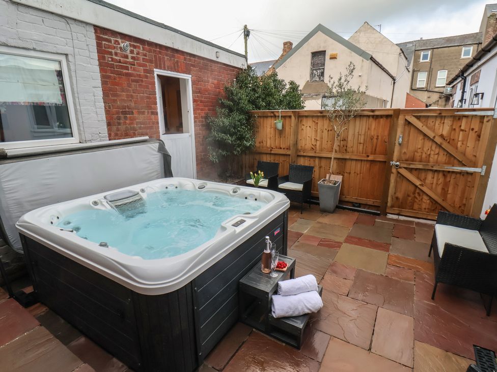 A hot tub with outdoor furniture in a patio area at Rutland Grange in Filey
