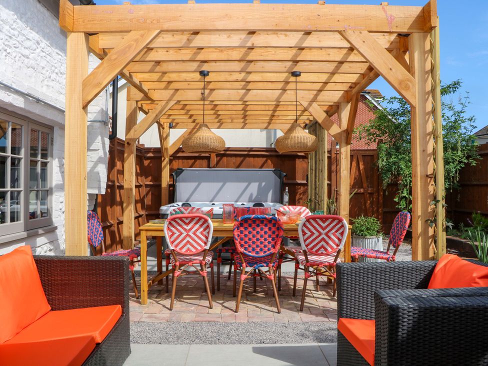 A garden with a pergola and outdoor dining area at Spring Cottage in Arundel, West Sussex