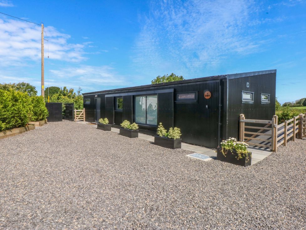 A house with a gravel driveway and planters at Y Cwt Moelfre