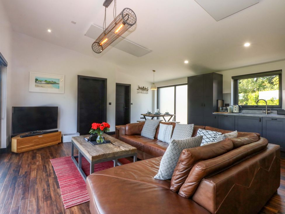 A living room with a sofa, coffee table, and TV at Y Cwt in Moelfre