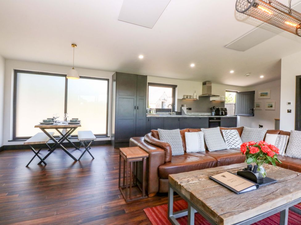 A living room with a sofa and dining area at Y Cwt in Moelfre