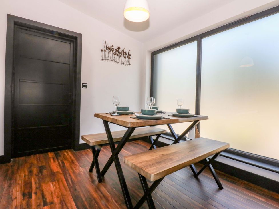A dining room with a wooden table and seating at Y Cwt Moelfre