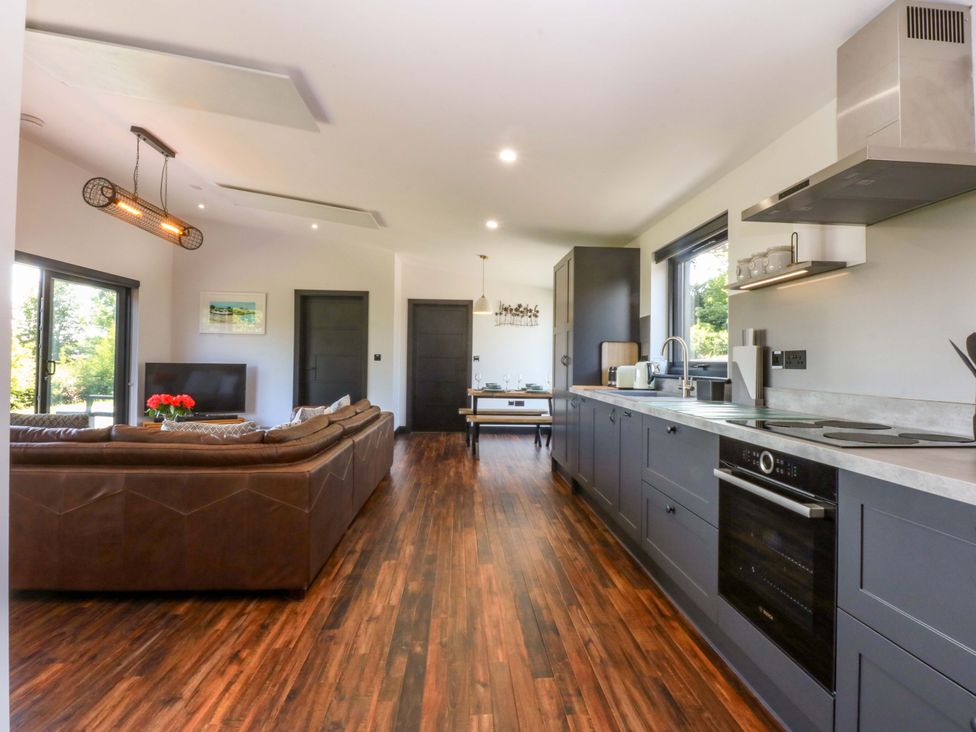 A living room with a sofa and kitchen area at Y Cwt in Moelfre
