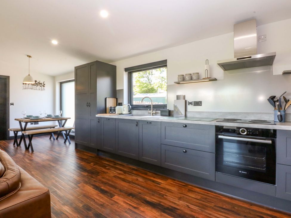 A kitchen with cabinets and a dining area at Y Cwt in Moelfre