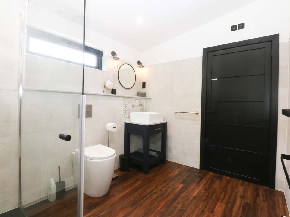 A bathroom with a shower, sink, and toilet at Y Cwt in Moelfre