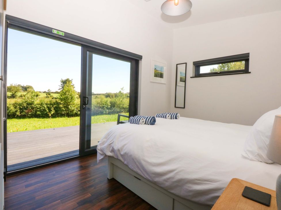 A bedroom with a bed and sliding door at Y Cwt in Moelfre