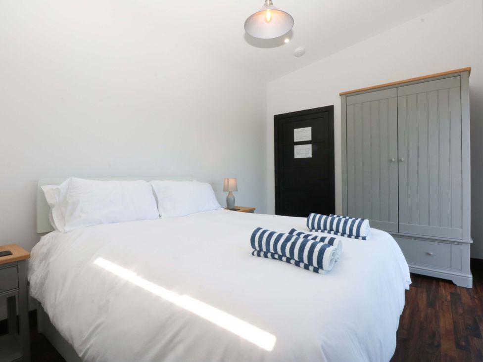A bedroom with a bed and wardrobe at Y Cwt in Moelfre