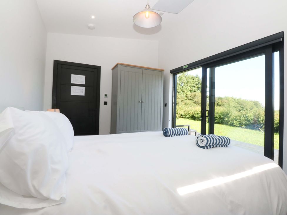 A bedroom with a bed and wardrobe at Y Cwt in Moelfre