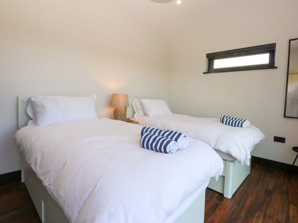 A bedroom with two beds and a lamp at Y Cwt in Moelfre