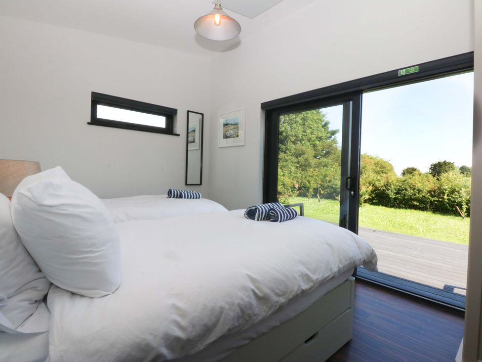 A bedroom with two beds and a view of the outside at Y Cwt in Moelfre