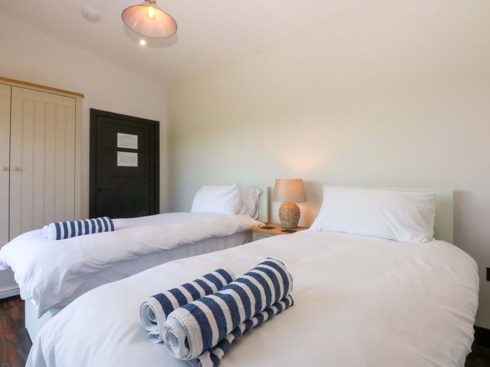 A bedroom with two beds and a lamp at Y Cwt in Moelfre