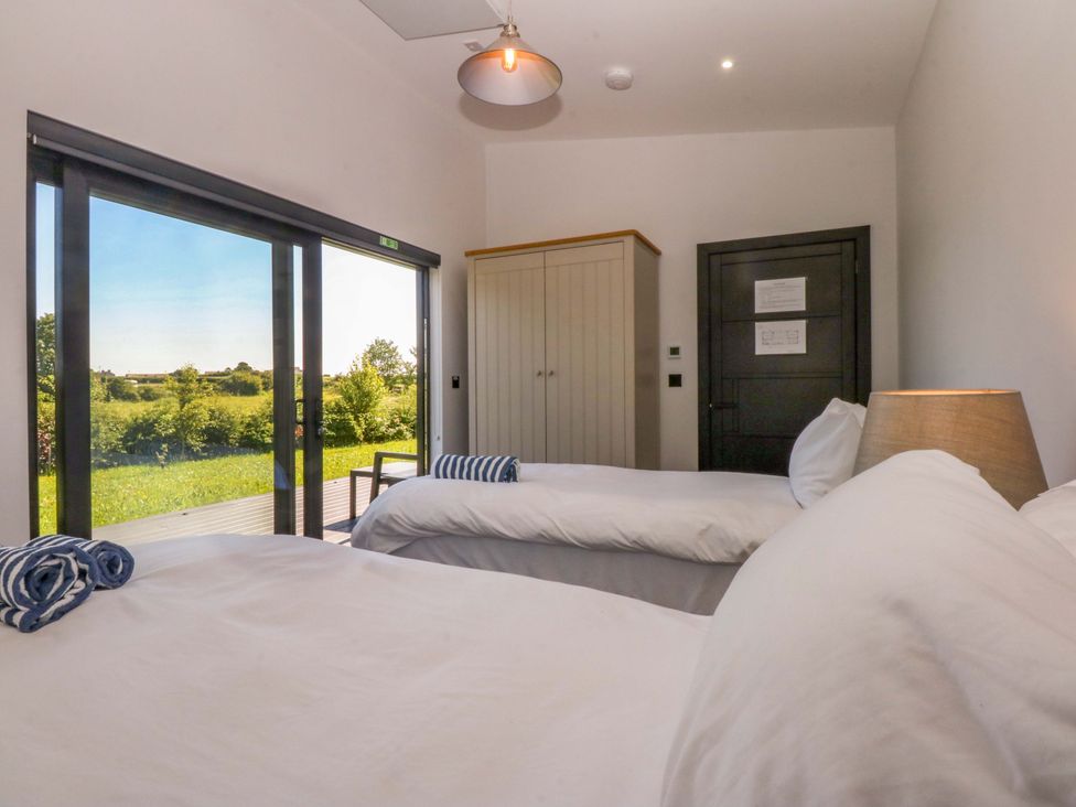 A bedroom with two beds and a wardrobe at Y Cwt in Moelfre