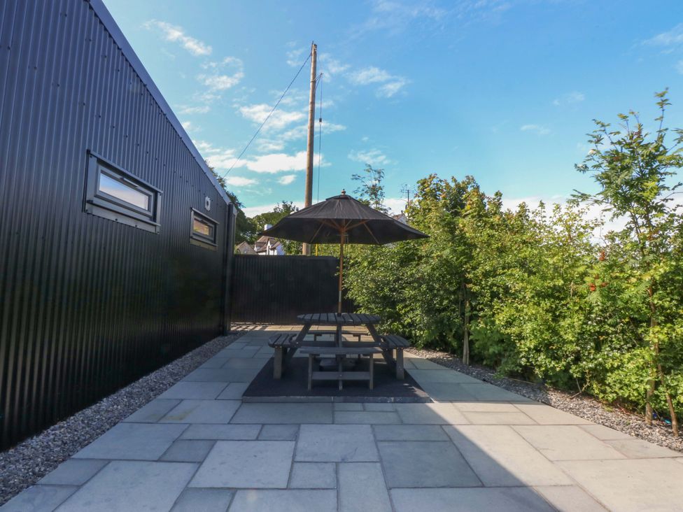 A garden with a table and umbrella at Y Cwt in Moelfre