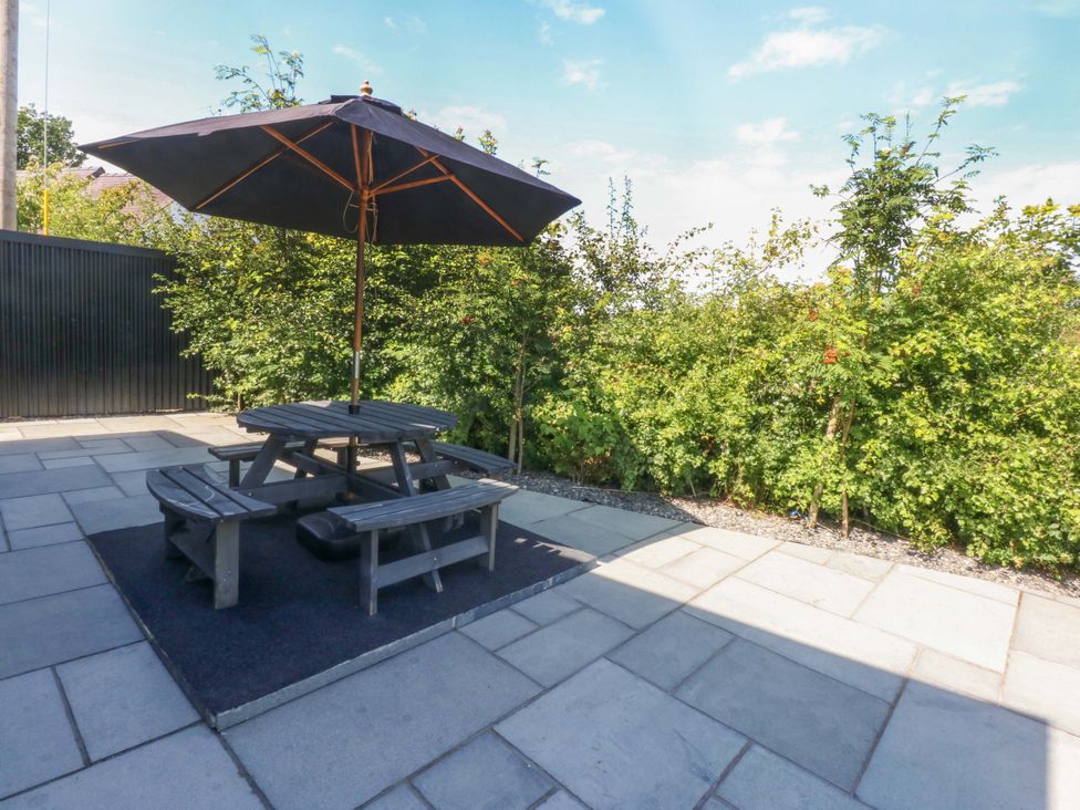 A garden with a table and benches under an umbrella at Y Cwt in Moelfre