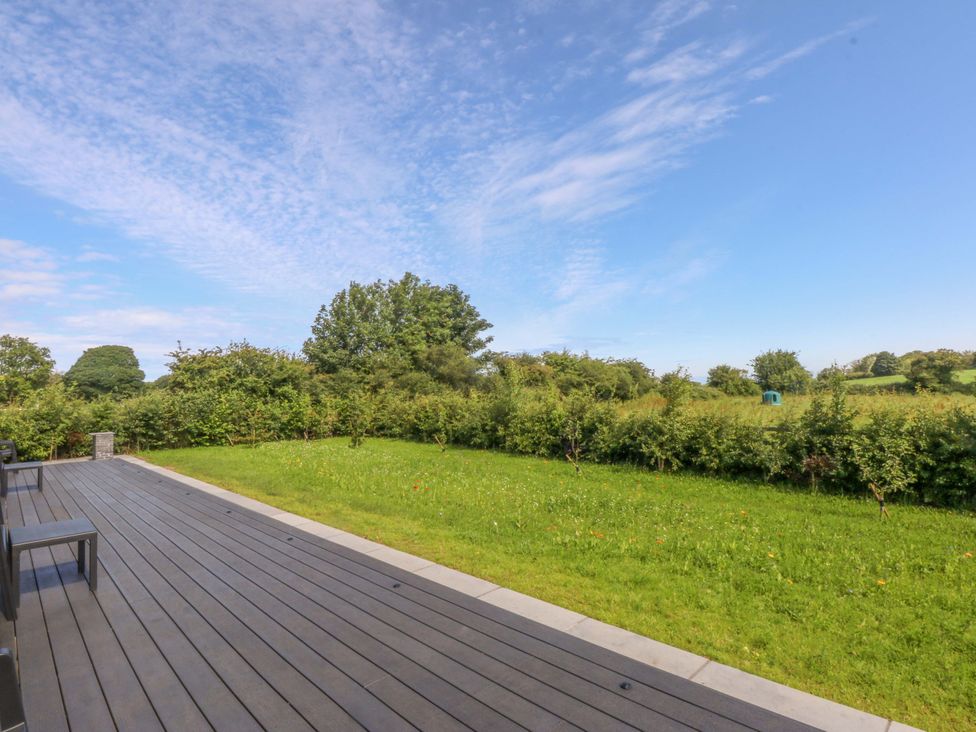 A garden with decking and grass at Y Cwt in Moelfre