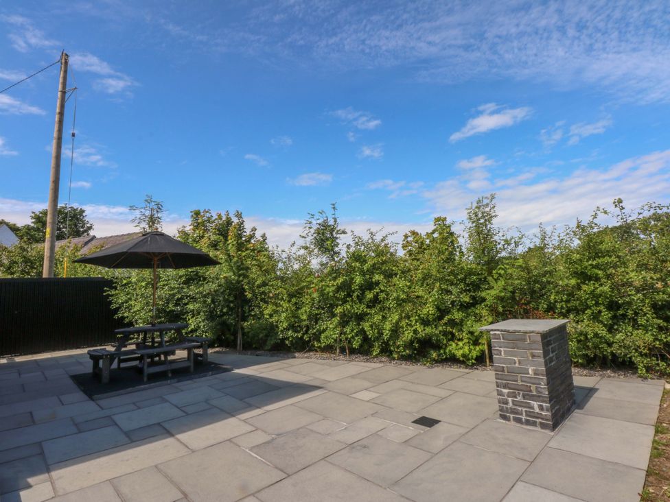 A garden with a picnic table and umbrella at Y Cwt in Moelfre