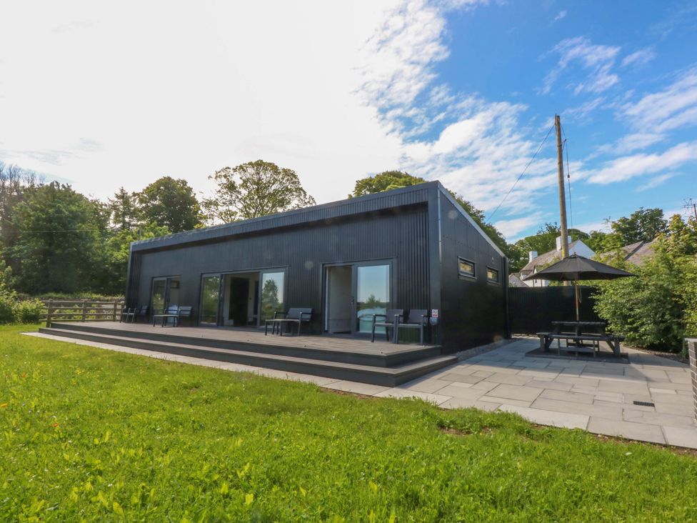 An outdoor view of a house with a patio and seating area at Y Cwt in Moelfre
