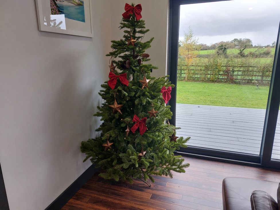 A Christmas tree with decorations and a view outside at Y Cwt in Moelfre