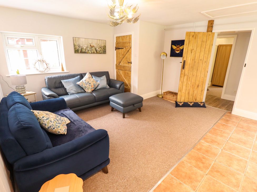A living room with a sofa, armchair, and door at Wood Farm Cottage Stickney near East Kirkby