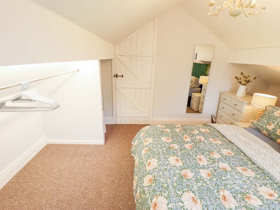 A bedroom with a bed and a mirror at Wood Farm Cottage in Stickney near East Kirkby