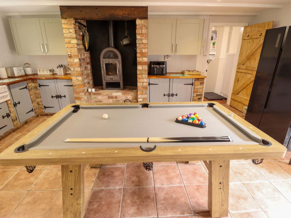 A kitchen with a pool table and a wood stove at Wood Farm Cottage Stickney near East Kirkby