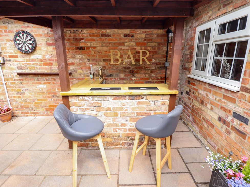 An outdoor bar with seating and a dartboard at Wood Farm Cottage Stickney near East Kirkby