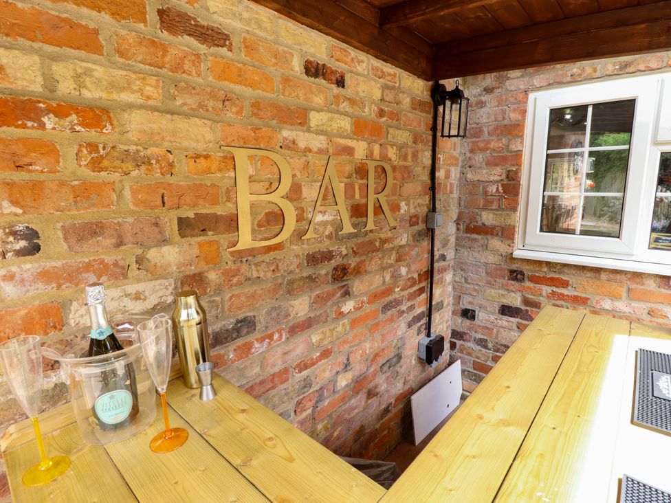 An outdoor bar area with wooden counter and champagne bottles at Wood Farm Cottage Stickney near East Kirkby