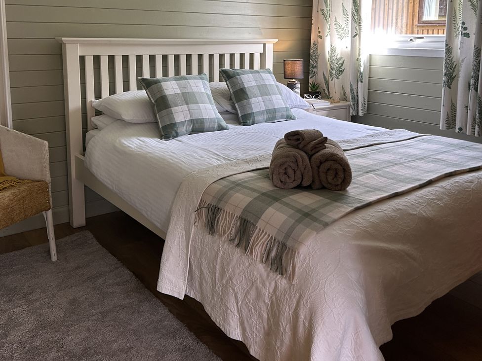 A bedroom with a bed, pillows, towels and a lamp at Number 39 in Bodmin
