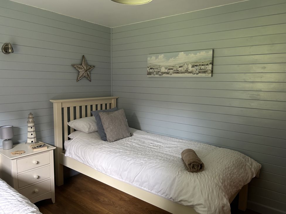 A bedroom with two beds and a side table at Number 39 in Bodmin