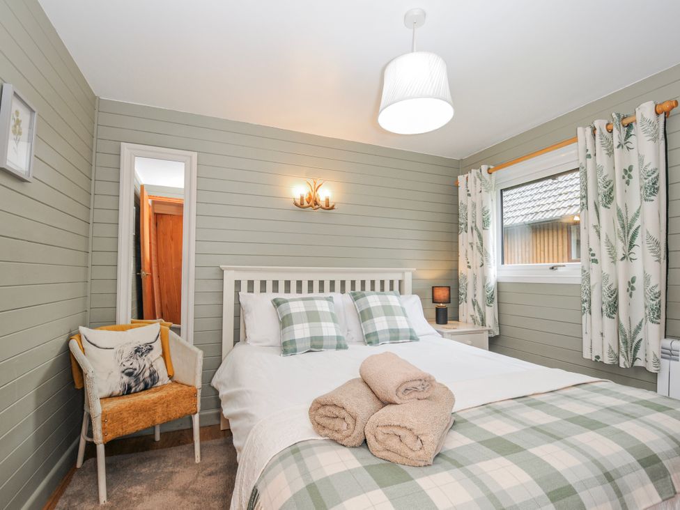 A bedroom with a bed, bedside table, and curtains at Cornish Woodland Retreat Near St Tudy